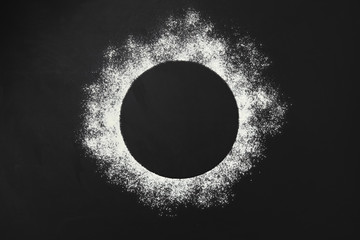 Flour powder on black background. Close up. Top view.