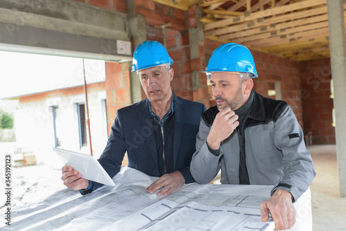 Architec and contractor checking the blue-prints on a construction site photo