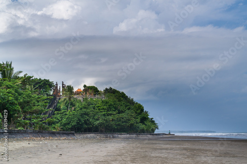 Pura Rambut Siwi, temple upon the sea in Bali, Indonesia; grey sand and sea with waves. cloudy sky