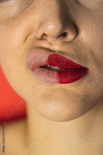 Close up of female lips with two different lipsticks. Red background