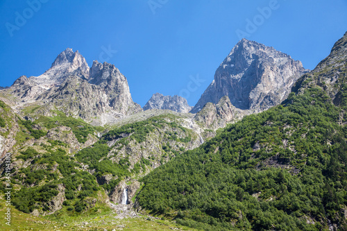 Mountain landscape with a waterfall, forest and blue sky. Copy space for text. 