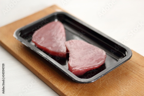 Raw tuna steak in disposable plastic packing box
