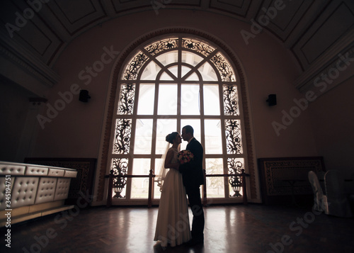 bride and groom near a large stained glass window