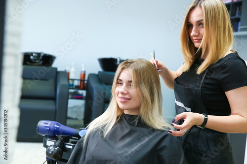 beautiful girl hairdresser makes a female haircut at the hairdresser