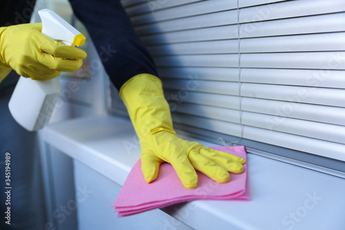 cleaner's hands in rubber yellow gloves doing disinfection cleaning with detergent spray and rag. preventive measures against covid-19