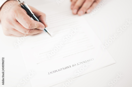 Closeup of a businessman signing an employment contract with a pen.