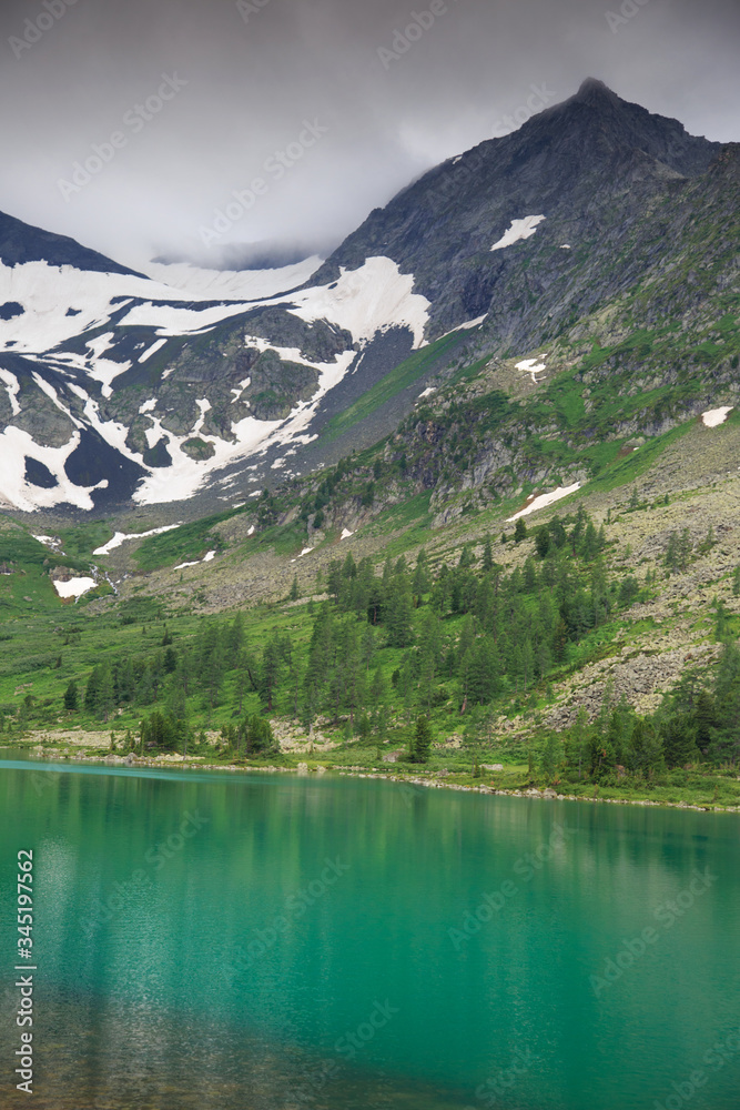 Shore of a clean mountain lake with mountain peaks in the background, Altai.
