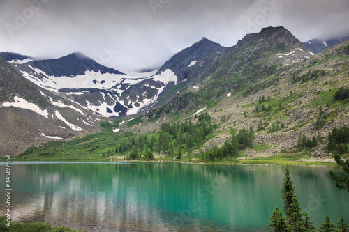 Shore of a clean mountain lake with mountain peaks in the background  Altai.