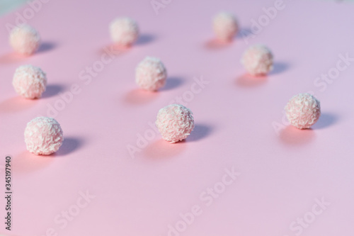 Sweet pink balls with coconut flakes on rose background as pattern