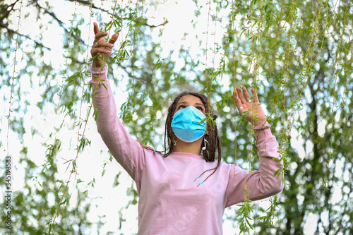Beautiful girl enjoys freedom and nature during COVID-19 pandemic while wearing protective mask