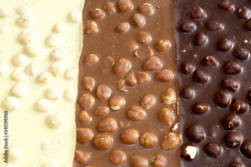 black, milk and white chocolate with nuts on a white background