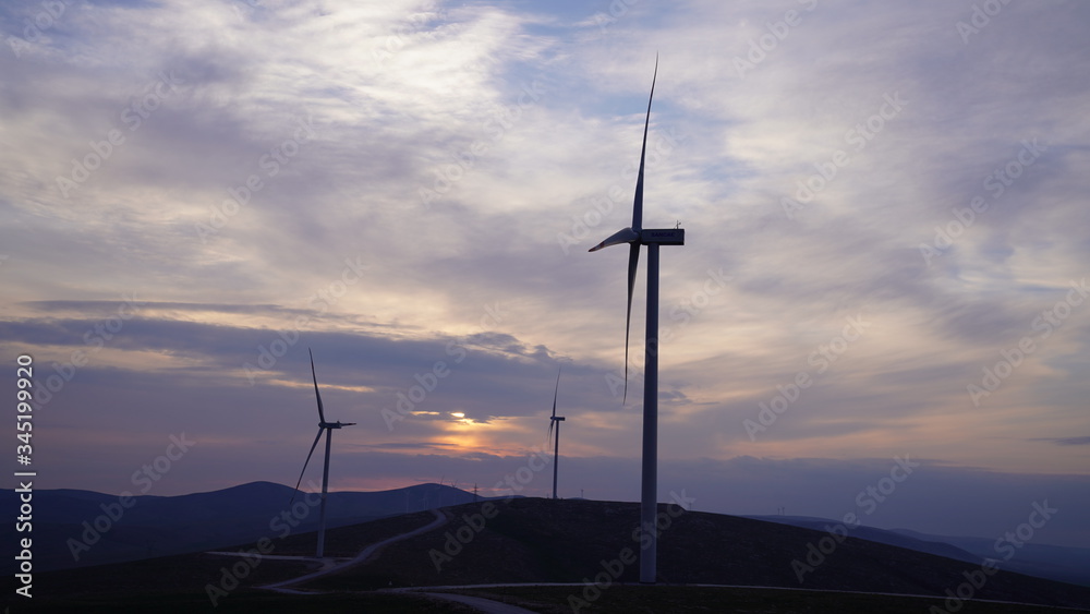 Wind turbines are generating power at sunset background. The concept of clean and renewable energy.