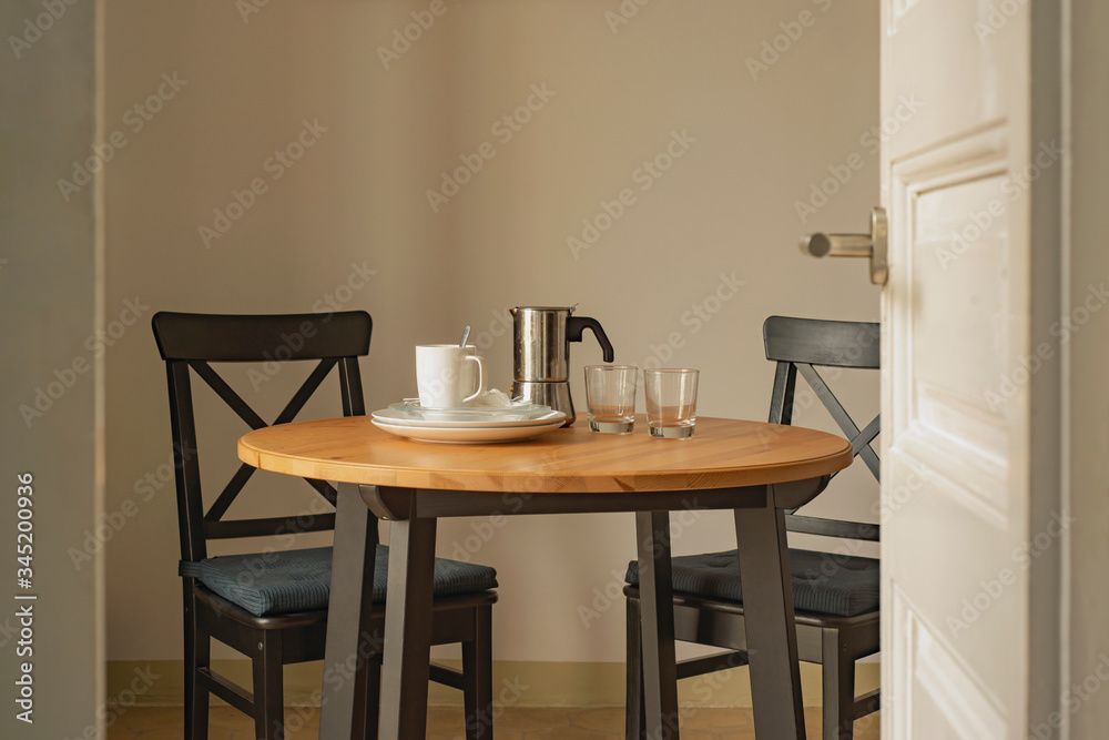 After breakfast home interior set with wooden table, black chairs, coffee maker, glasses, and empty dishes After breakfast home interior set with wooden table, black chairs, coffee maker, glasses, and empty dishes