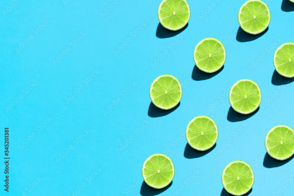 Summer abstract trendy fresh concept. Lime pattern on bright light blue background, copy space. Minimal flat lay food texture.