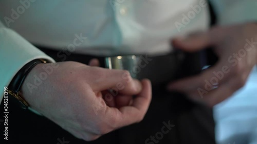 a man removing the black belt of his trousers