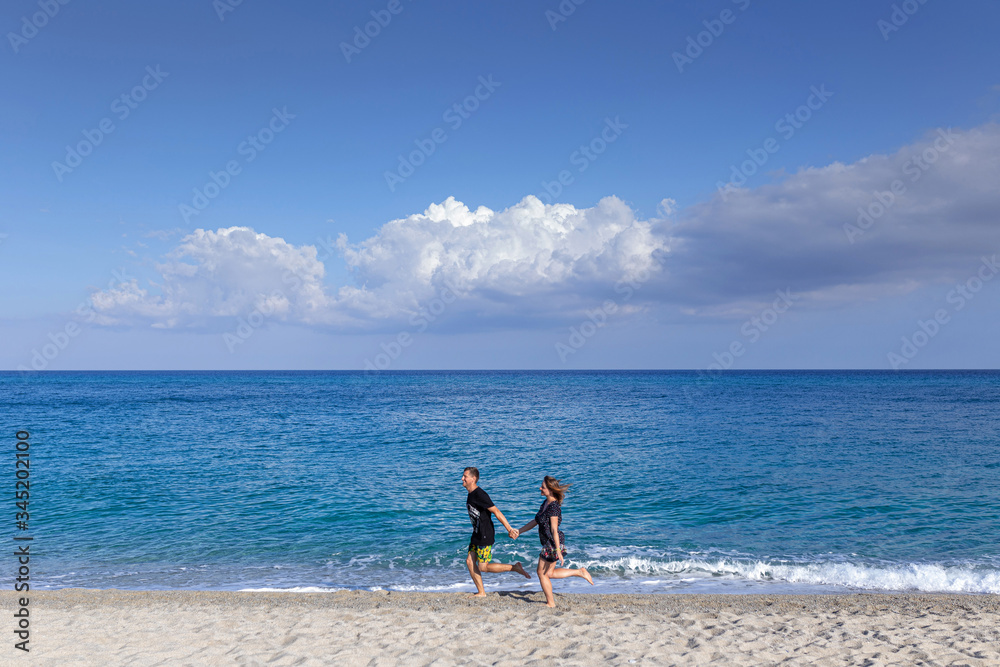 couple on beach in summer with clear blue sea on background