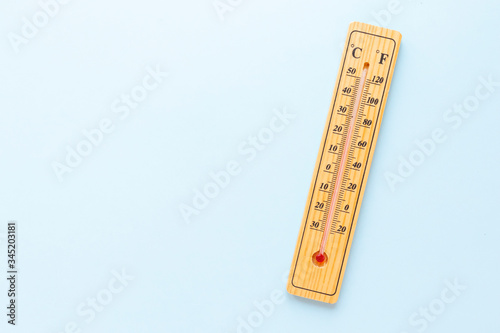 A classic wooden thermometer on blue background doesn't show any temperature. Copy space