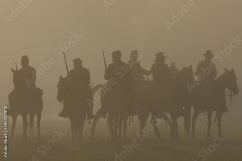 American Civil War horseback riders prepare to advance in battle. Silhouetted by a smoky haze.
