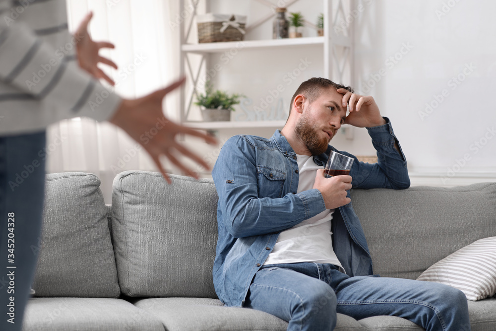 Angry woman quarreling with her drinking husband at home Angry woman quarreling with her drinking husband at home