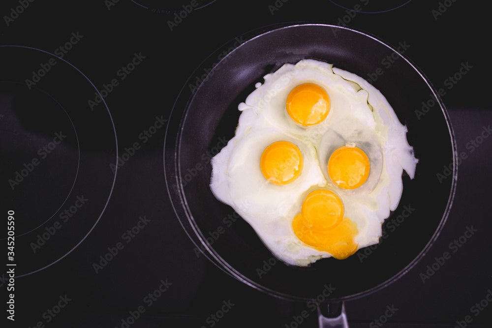 Fried eggs in frying pan. Four eggs. Making breakfast for family. Family weekend breakfast. Quick easy brunch breakfast. Over medium fried eggs. Egg yolk, egg whites. Black stove top. Broken egg yolk Fried eggs in frying pan. Four eggs. Making breakfast for family. Family weekend breakfast. Quick easy brunch breakfast. Over medium fried eggs. Egg yolk, egg whites. Black stove top. Broken egg yolk