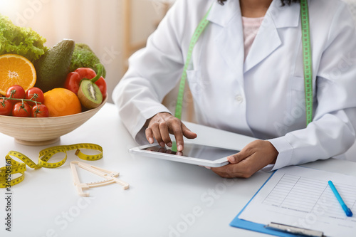 Black woman dietician working with digital tablet at clinic