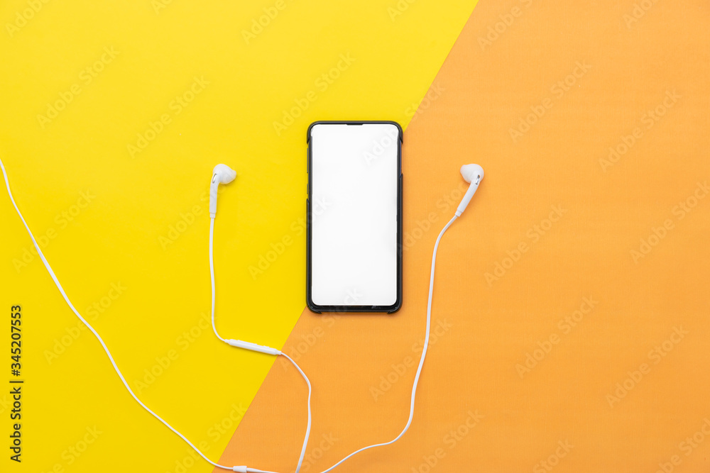 Obraz premium White headphones with the phone isolated on yellow/orange background.