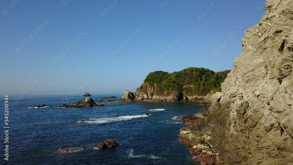 Drone making a flyby along dramatic Mexican coastal cliffs and out towards a secluded bay.