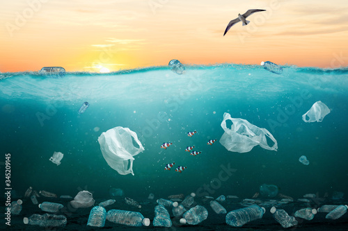 Environmental problem with plastic pollution in ocean illustrated by sunrise over sea full of plastic bottles and plastic bags.