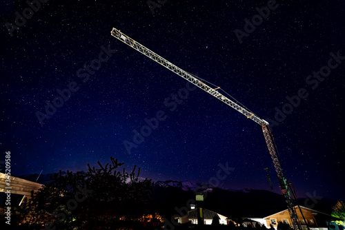 Crane over houses during dark cloudless night with stars