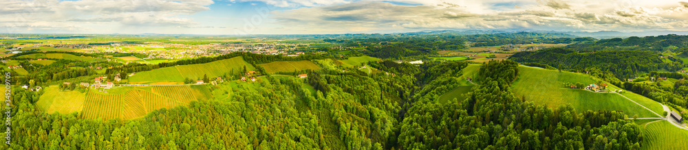 Aerial panorama of of green hills and vineyards with Leibnitz in background.
