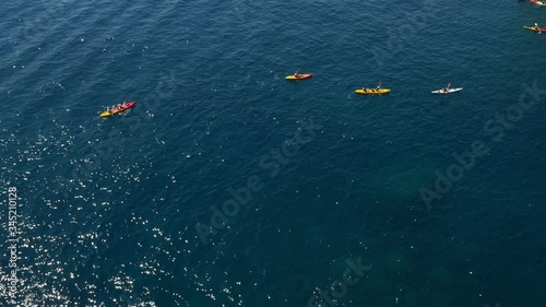 Long shot aerial shot of a large group of sea kayakers following their leader in the open sea