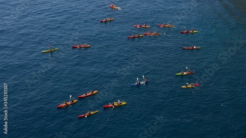 Long shot aerial shot of a large group of sea kayakers following their leader in the open sea