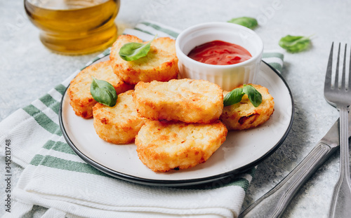 Hash brown or potato pancakes on plate with catsup on light gray background