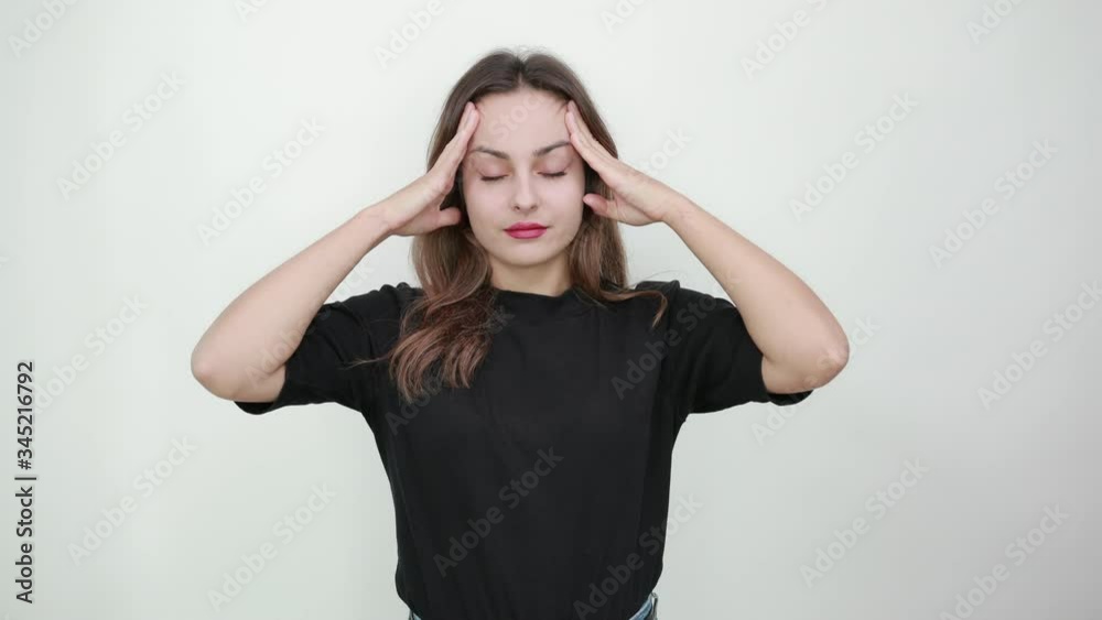 Cute Young Brunette Woman In Black T-Shirt, Blue Jeans With Belt On Gray Background, Tired Girl With Pain And Impotence Holding Her Head With Hands Cute Young Brunette Woman In Black T-Shirt, Blue Jeans With Belt On Gray Background, Tired Girl With Pain And Impotence Holding Her Head With Hands