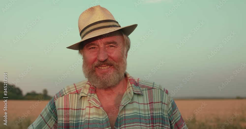 Portrait of happy senior farmer in hat smiling at camera in sunny field Portrait of happy senior farmer in hat smiling at camera in sunny field