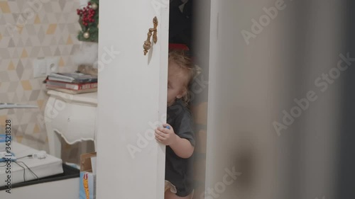 Toddler girl wants to play hide-and-seek so she hiding in the wardrobe and waiting for mum to find her