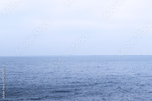 Blue sea water turns into a blue sky, foggy. The skyline is clearly visible in the photo. © Ievgeniia