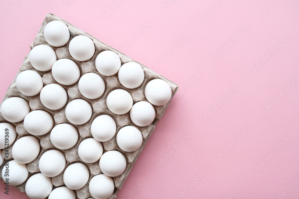 Chicken eggs in egg carton tray with rooms for thirty eggs on pink background. Top view. Chicken eggs in egg carton tray with rooms for thirty eggs on pink background. Top view.
