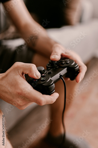 Hipster man plays video games on a couch. Relaxing time. Fun weekend. Concentrated on a video game. Winning the game, gambling. Multiplayer game. Online gaming. Streaming video game. Soccer, racing