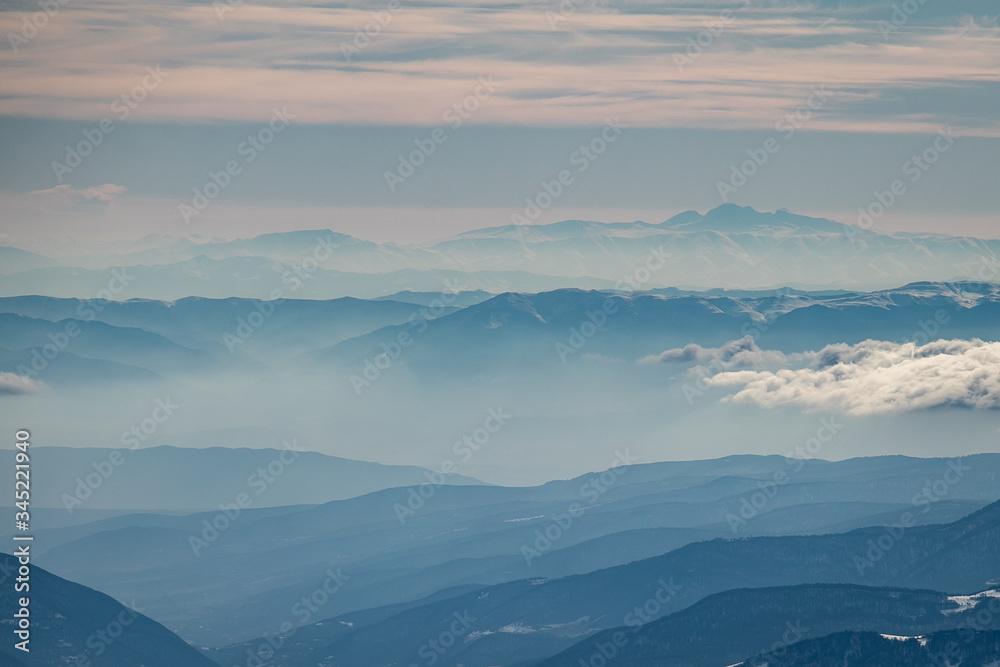 Caucasian mountains in layers in a beautiful foggy haze. 
Landscape