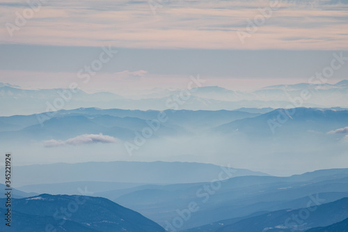 Beautiful landscape of the Caucasus mountains in a foggy haze of clouds © Lisitskiyfoto