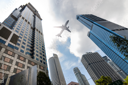 Photography Air plane flying low over highrise office buildings in downtown of Singapore Cit