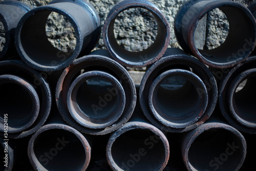 Iron barrels are arranged in a regular pattern in the street. Textured background.
