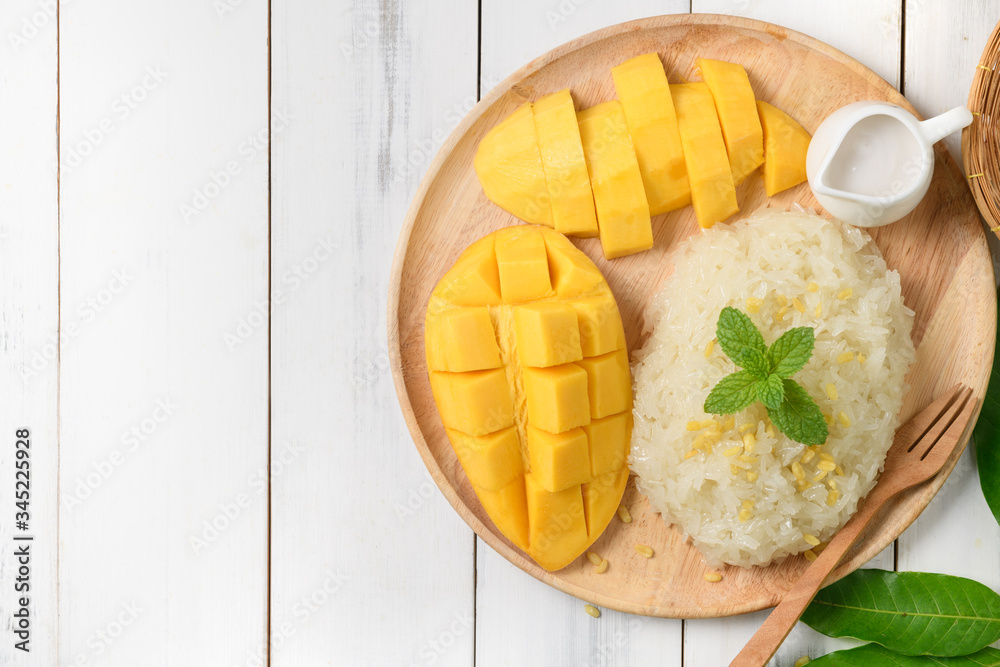 Ripe mango and sticky rice with coconut milk on white wood background