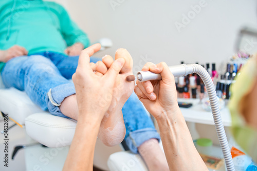 woman master pedicures a man. Hardware pedicure. Leg close up. A man sits in a pedicure chair