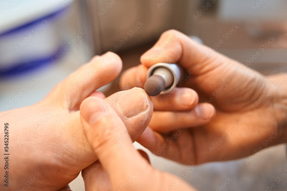 Fototapeta premium woman master pedicures a man. Hardware pedicure. Leg close up. A man sits in a pedicure chair