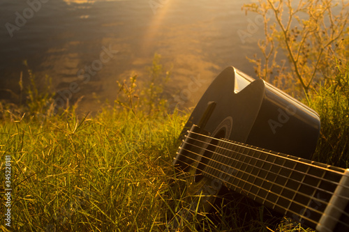 Black guitar in grass at sunset