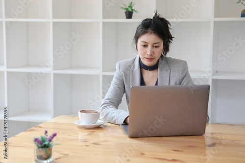 Young caucasian businesswoman working on laptop with hot coffee at wooden desk in lockdown. work from home.
