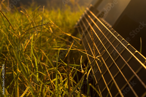 Black guitar in grass at sunset