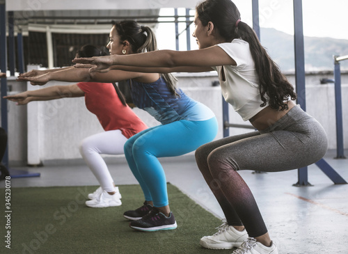 three women exercise in the gym doing squat
